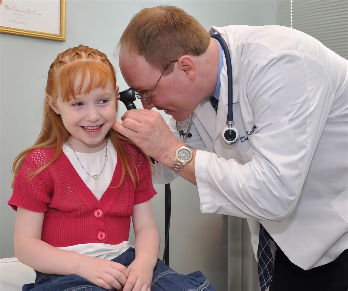Doctor examining a smiling young girl's ears